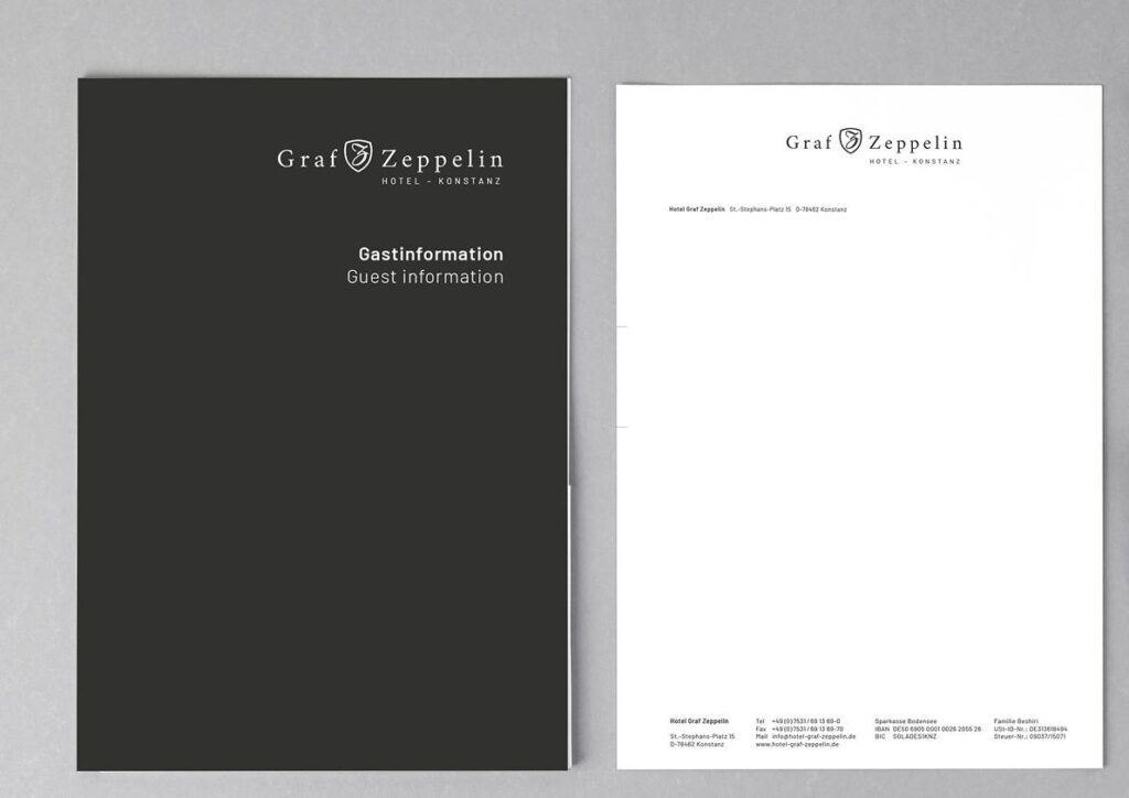 Dunkle Gästemappe „Gastinformation“ und Briefbogen mit Logo des Hotels Graf Zeppelin