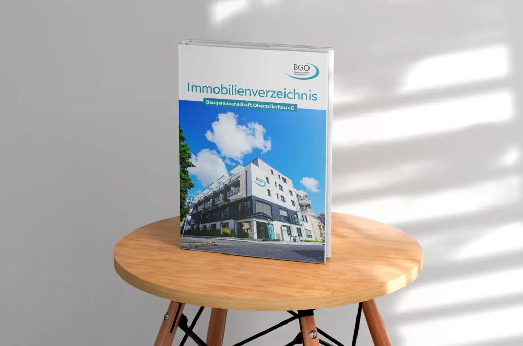 Titelseite des Immobilienverzeichnisses der Baugenossenschaft Oberzellerhau eG auf einem kleinen Holztisch